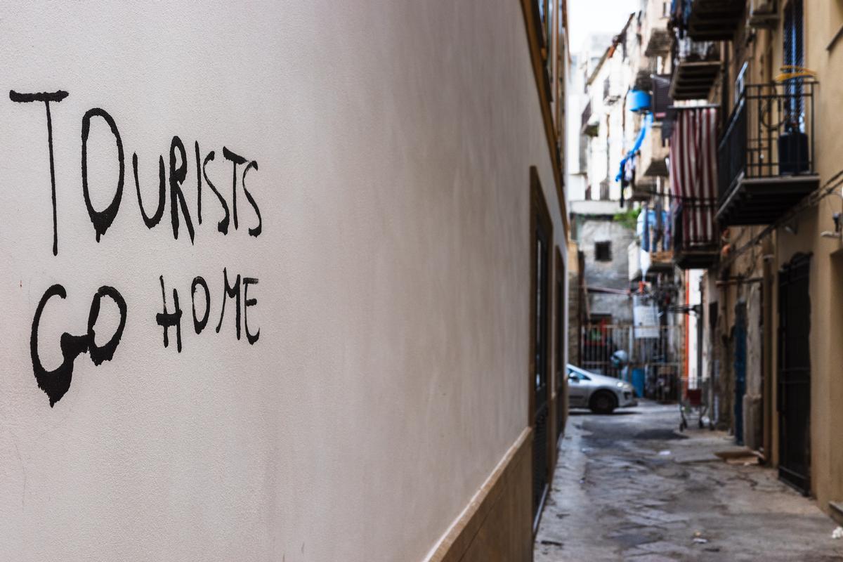 Una scritta contro la turistificazione sul muro di una palazzina al mercato palermitano di Ballarò
