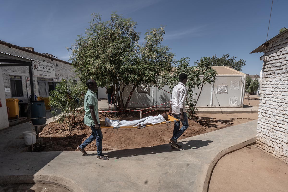 Tawila (Sudan), 28 febbraio 2026. Due operatori di Medici senza frontiere trasportano un giovane in barella in uno dei pochi ospedali funzionanti. Foto di Giles Clarke/Ocha