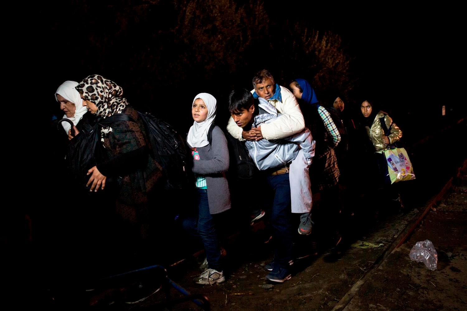 Un giovane afgano trasporta il padre sulle spalle lungo il confine serbo-ungherese, alle 23:50 del 14.09.15. A mezzanotte le autoritÃ  chiuderanno la frontiera. Foto di Valerio Muscella