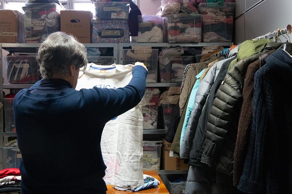 Una volontaria mette ordine ai vestiti nello spazio guardaroba gestito da Rete Milano, situato nel quartiere Ortica, dove i migranti in transito possono prendere capi d'abbigliamento o scarpe, oppure fare una doccia e ricevere piccole cure infermieristiche (Foto di Marta Facchini)