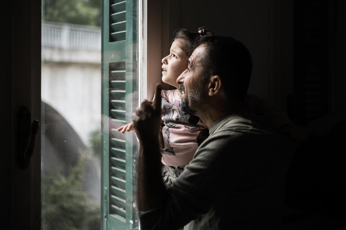 Rossiglione, 26 settembre 2025. Mohammed tiene in braccio Risal, preoccupata dal rumore di un elicottero che sta sorvolando la loro nuova casa. Foto di M. Panzarella