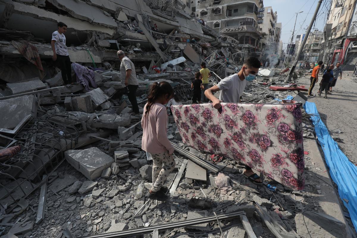 Gaza City, 8 ottobre 2023. Un gruppo di palestinesi tra le macerie della Torre Aklouk, distrutta dagli attacchi aerei israeliani/Wafa