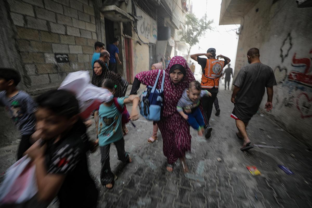 Gaza, 23 ottobre 2023. Una mamma palestinese fugge dai bonmbardamenti insieme ai suoi figli. Foto di Mohammed Saber/Epa
