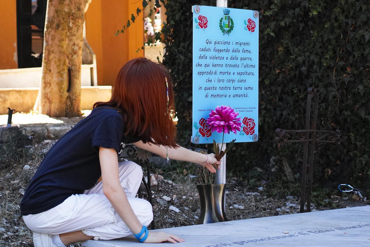 Santo Stefano Quisquina, 10 agosto 2023. Una ragazza posa un fiore sulla lapide senza nome dei migranti morti a Lampedusa, che hanno trovato degna sepoltura nel cimitero del piccolo comune siciliano. Foto M. Panzarella