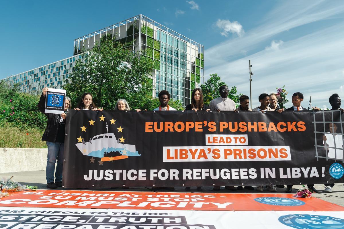 L'Aia (Paesi Bassi), 21 maggio 2026. Attiviste e attivisti espongono uno striscione che denuncia la complicità dell'Europa nei crimini nei centri di detenzione in Libia. Il sesto da sinistra è Lam Magok. Foto di Refugees in Libya