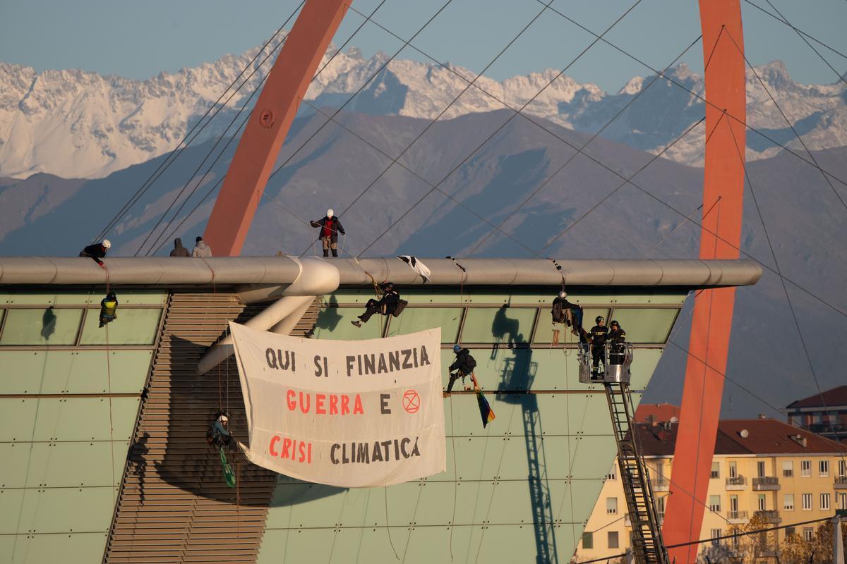 Torino, 29 novembre 2023. Attivisti di Extinction Rebellion durante una azione di disobbedienza civile nonviolenta all'Oval espongono lo striscione "Qui si finanzia guerra e crisi climatica". Extinction Rebellion