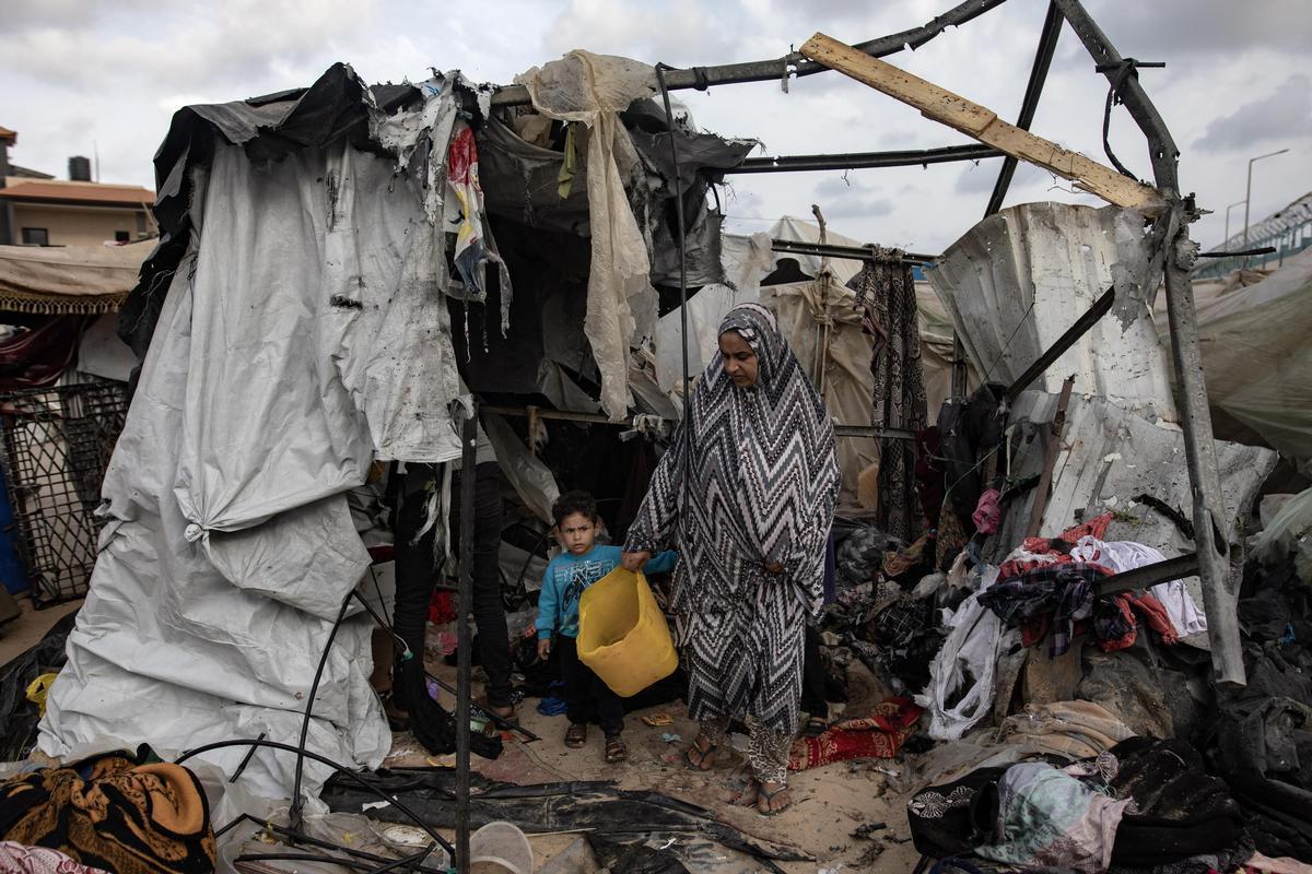 Rafah, 28 May 2024. A woman and her child look at what remains of their tent after an Israeli attack. Photo Haitham Imad/EPA