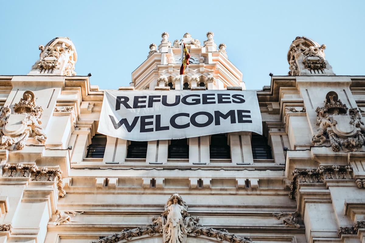 Lo strisicone "Refugees welcome" sulla faccia di Palacio del Cibeles, a Madrid (Maria Teneva/Unsplash)