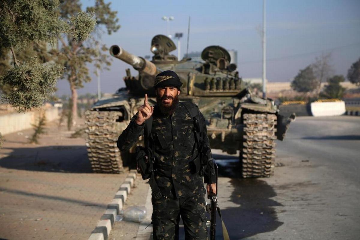 Aleppo, 2 dicembre 2024. Un miliziano jihadista posa davanti a un carro armato dopo che le forze ribelli hanno preso il controllo della città. Foto di B. Al Hammoud/Epa/Ansa