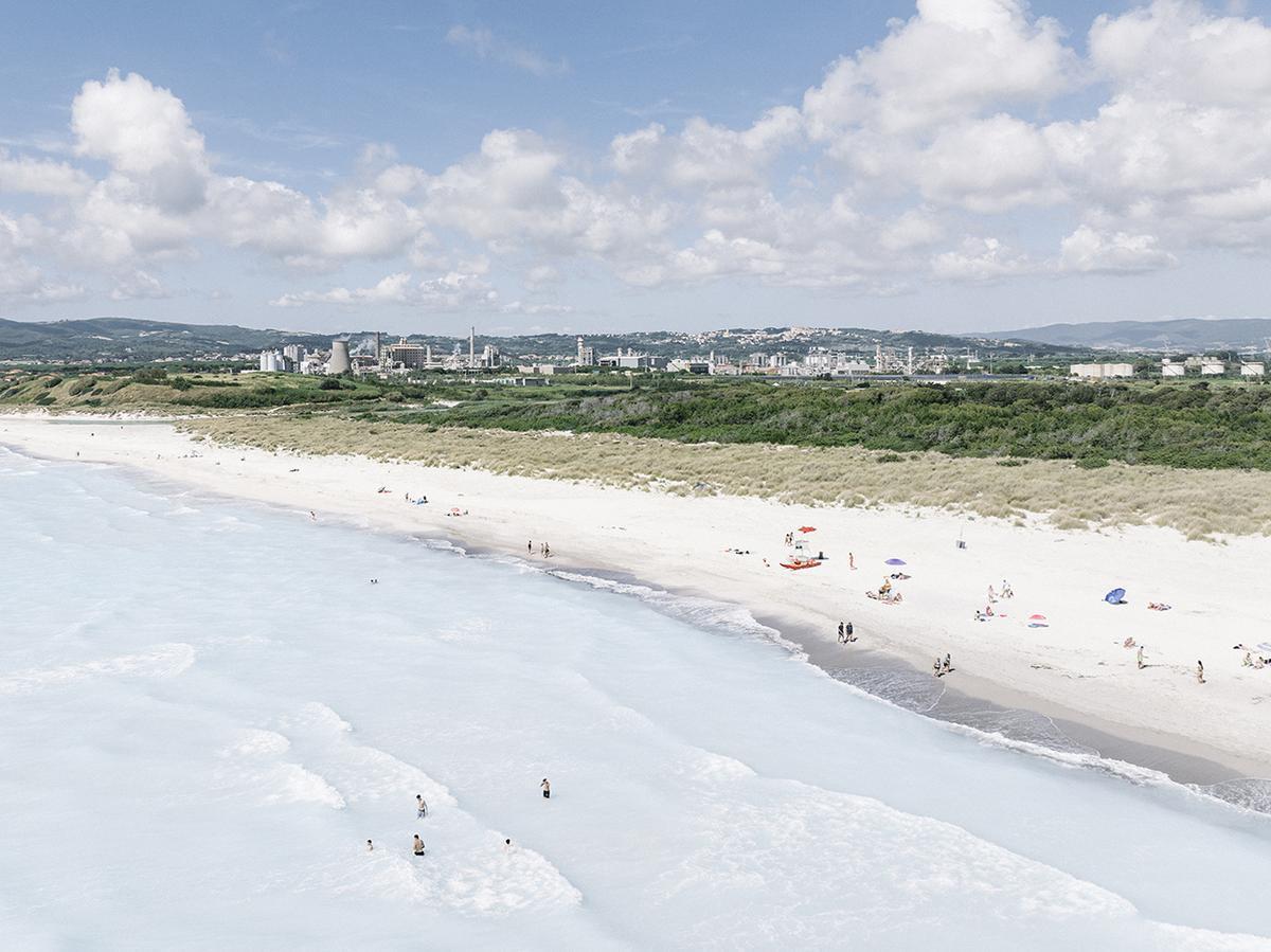 Giugno 2026. Spiagge Bianche, Rosignano Solvay. Veduta aerea della costa bianca e dello stabilimento Solvay dietro le dune. Nonostante il punto di scarico sulla spiaggia e i divieti di balneazione e transito entro 100 metri, residenti e turisti continuano a frequentare la spiaggia © Melanie Wenger/Inland
