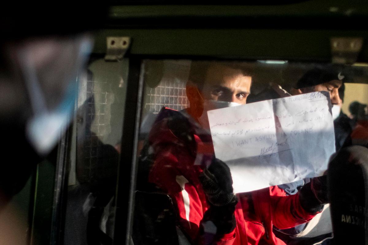 Aland, un iracheno di 20 anni, viene portato via dalla Guardia di frontiera. Regge un foglio con scritto: "Voglio asilo in Polonia". Credits: Epa/Martin Divisek 
