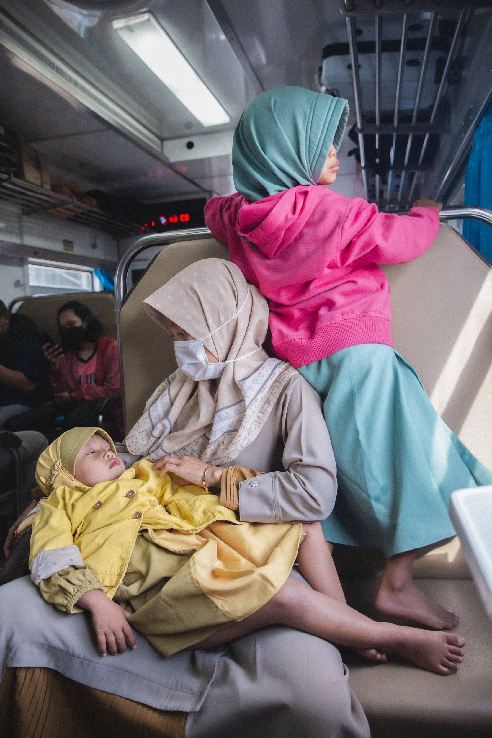 Una famiglia indonesiana in un vagone di prima classe con aria condizionata su un treno che va da Tegal a Yogyakarta, Java. Indonesia, 2022 - Umidità 80%, Temperatura 25°C. Foto di Gaia Squarci 