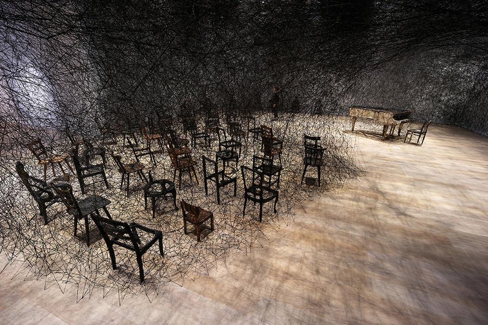 Shiota Chiharu, In Silence 2002/2019 Burnt piano, burnt chair, Alcantara black thread Dimensions variable Production support: Alcantara S.p.A. Installation view: Shiota Chiharu: The Soul Trembles, Mori Art Museum, Tokyo, 2019 Photo: Sunhi Mang Photo courtesy: Mori Art Museum, Tokyo