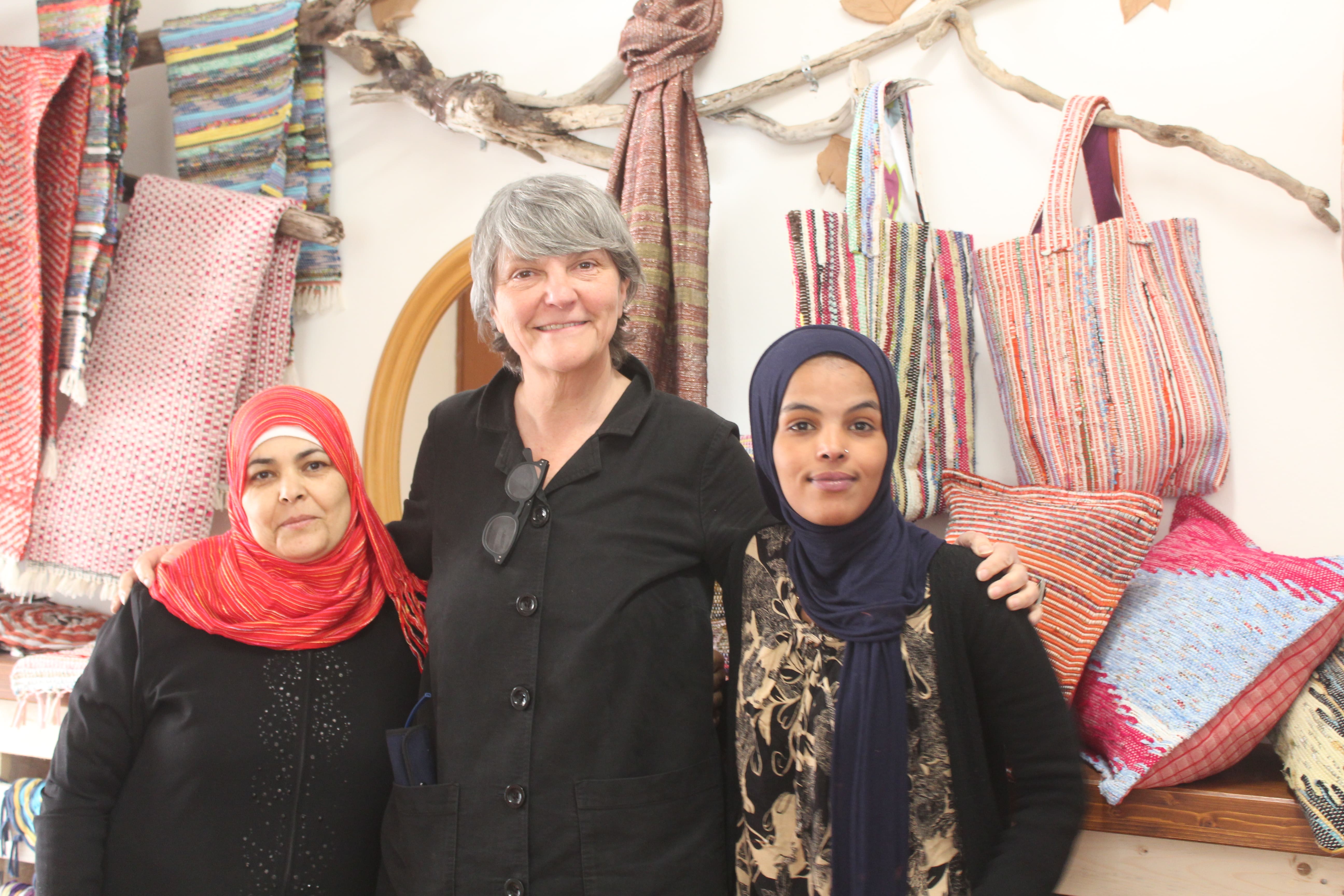 Due giovani rifugiate insieme all'insegnante di telaio Caterina Niutta