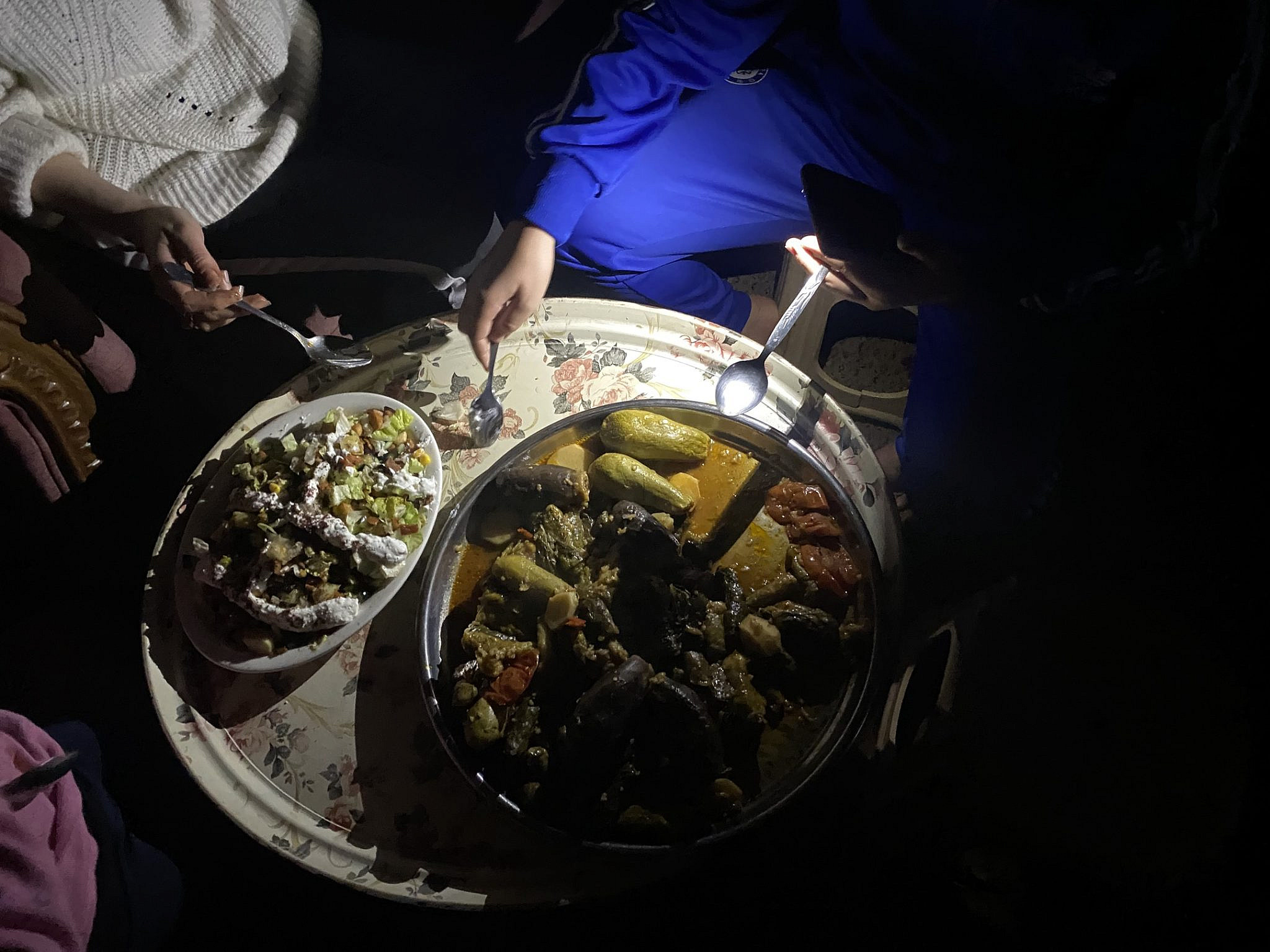 Gaza City, 17 marzo 2025. Ahmad Dremly e la sua famiglia consumano l'Iftar alla luce delle torce del telefono