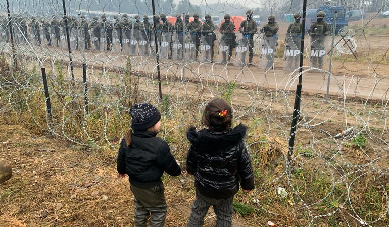 Confine tra Bielorussia e Polonia. Due bimbe davanti al filo spinato sorvegliato dai soldati di Varsavia. Ansa 