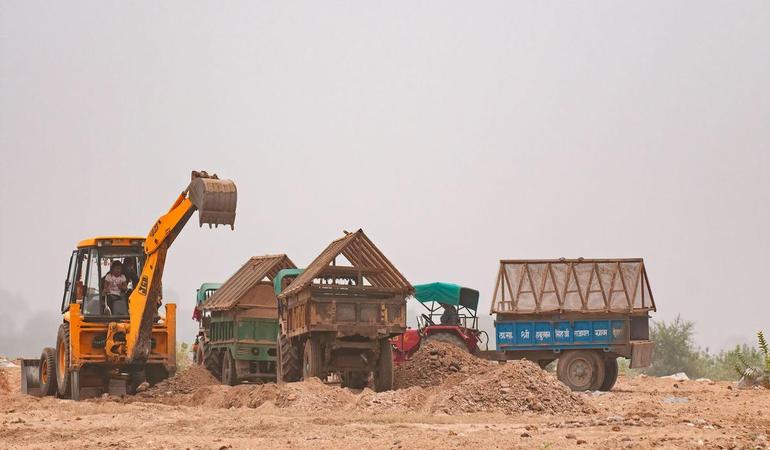 Parco nazionale Ranthambore, Rajasthan (India). Una ruspa carica sui camion la sabbia estratta illegalmente dal fiume Banas (Dinodia Photos/Alamy Foto Stock)