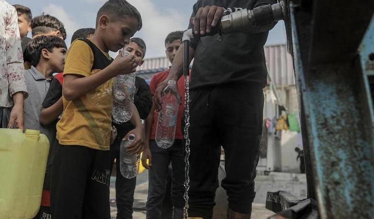 Gaza, 22 ottobre 2023. Un gruppo di bambini residenti del campo di Khan Yunis fanno la fila per riempire i contenitori di una cisterna d'acqua. Foto di Haitam Imad/Epa