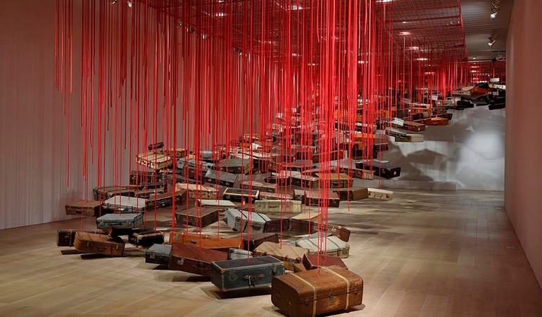 Shiota Chiharu, Accumulation - Searching for the Destination 2014/2019 Suitcase, motor and red rope Dimensions variable Installation view: Shiota Chiharu: The Soul Trembles, Mori Art Museum, Tokyo, 2019 Photo: Kioku Keizo Photo courtesy: Mori Art Museum, Tokyo