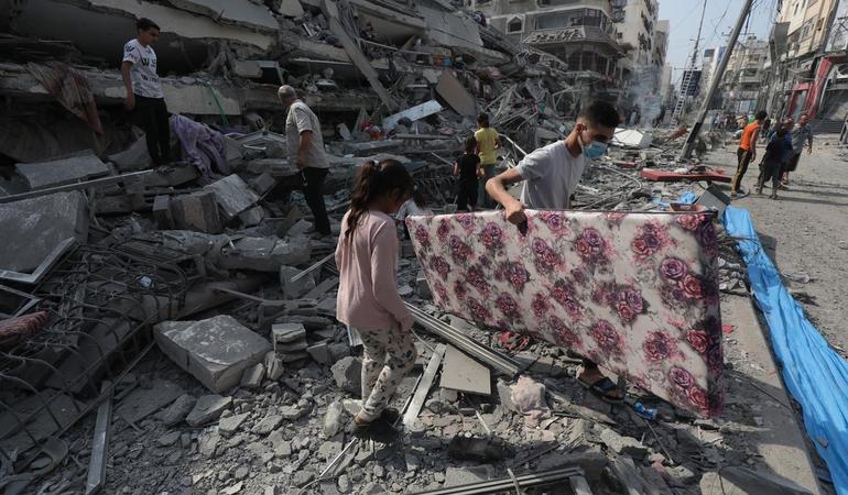 Gaza City, 8 ottobre 2023. Un gruppo di palestinesi tra le macerie della Torre Aklouk, distrutta dagli attacchi aerei israeliani/Wafa