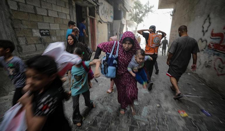 Gaza, 23 ottobre 2023. Una mamma palestinese fugge dai bonmbardamenti insieme ai suoi figli. Foto di Mohammed Saber/Epa