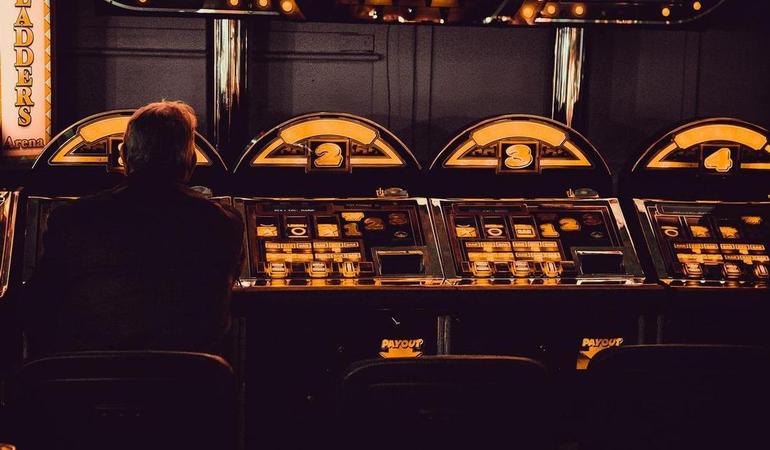 Un giocatore davanti alle slot di un casinò (Carl Raw - Unsplash)