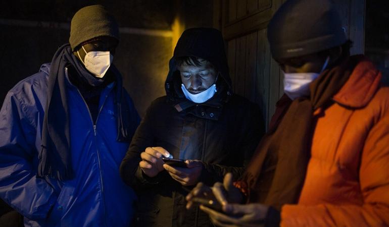 Due ragazzi della Costa d'Avorio e un ragazzo afgano controllano una mappa Gps con il percorso da seguire per raggiungere a piedi la Francia. Foto: Michele Lapini 