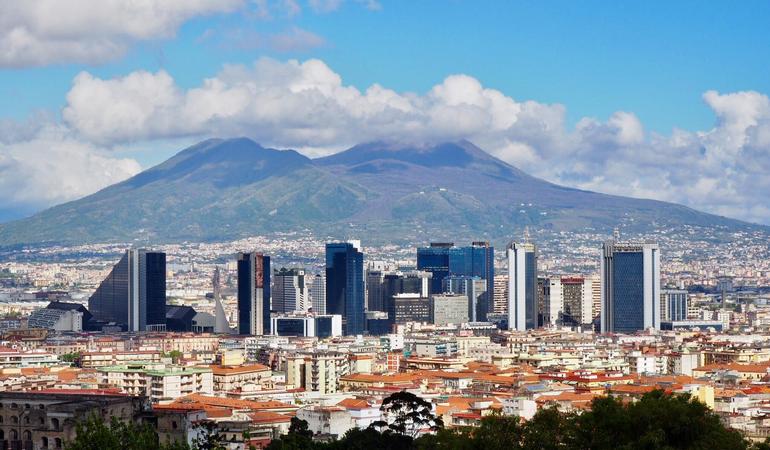Il centro direzionale di Napoli e, dietro, il Vesuvio (Wikipedia) 