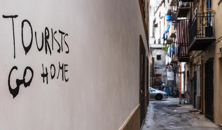 Una scritta contro la turistificazione sul muro di una palazzina al mercato palermitano di Ballarò