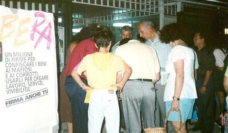 Un gruppo di persone partecipa nel 1995 alla raccolta firme per la legge sui riuso sociale dei beni confiscati alle mafie
