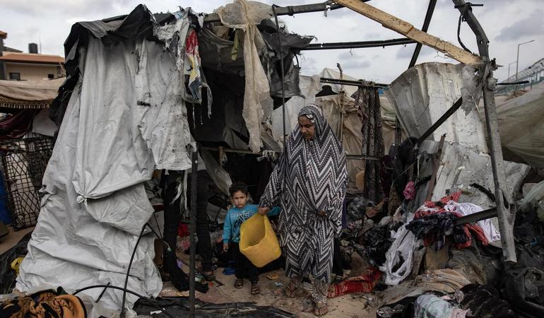 Rafah, 28 May 2024. A woman and her child look at what remains of their tent after an Israeli attack. Photo Haitham Imad/EPA