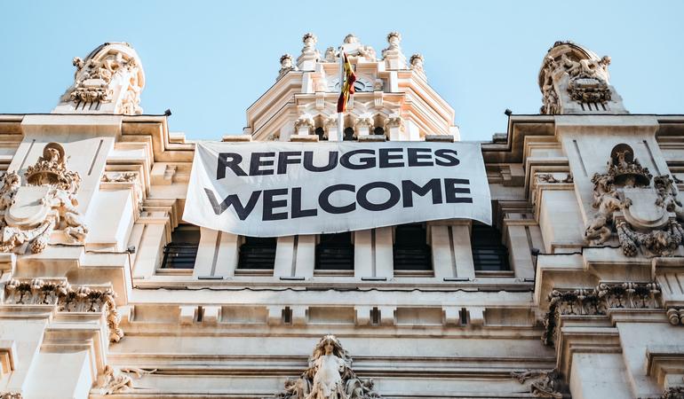 Lo strisicone "Refugees welcome" sulla faccia di Palacio del Cibeles, a Madrid (Maria Teneva/Unsplash)