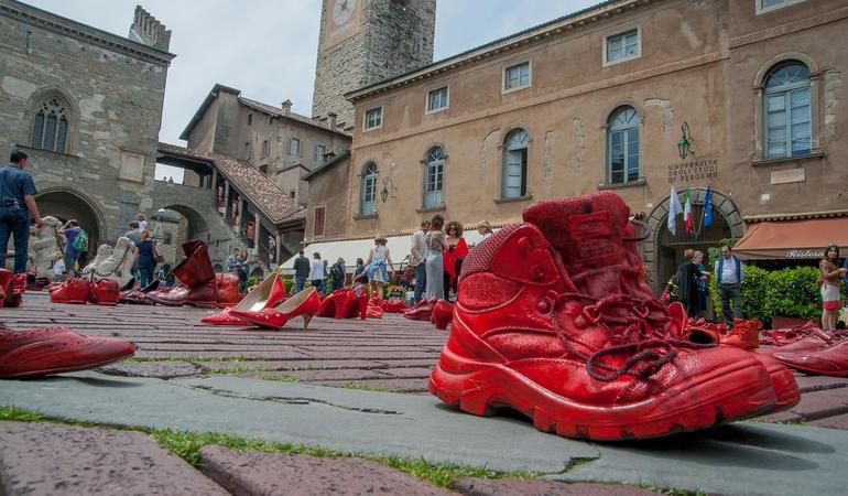 Bergamo, piazza Vecchia. Le scarpe rosse in ricordo delle vittime delle violenza di genere (Foto di Pierluigi Palazzi da Vecteezy) 