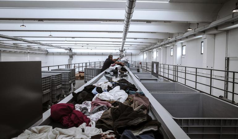 Rho (Milano). Un operatore della cooperativa Vesti solidale smista i vestiti arrivati dalla raccolta dei cassonetti gialli