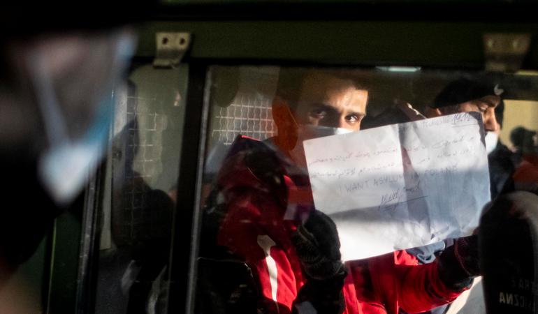 Aland, un iracheno di 20 anni, viene portato via dalla Guardia di frontiera. Regge un foglio con scritto: "Voglio asilo in Polonia". Credits: Epa/Martin Divisek 