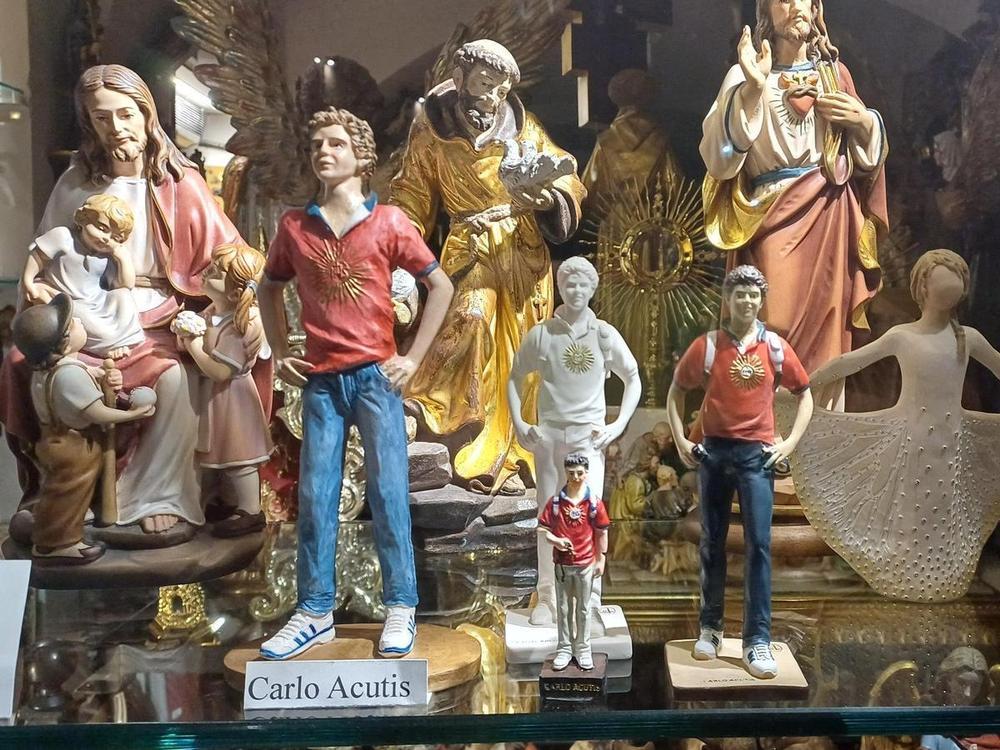 Alcune statuette di San Carlo Acutis in vendita ad Assisi, città in cui è esposto il corpo del giovane