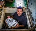 Un pescatore mostra una cassetta di pesce destinata alla vendita
