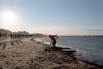 A fine giornata, un dipendente di uno stabilimento balneare pulisce e ripiana la spiaggia