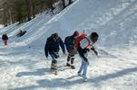 Quattro ragazzi attraversano il confine tra Claviere e Monginevro camminando su una pista da sci