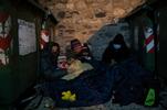 Una famiglia afgana si ripara dal freddo tra i bidoni della spazzatura prima di partire verso il confine italo-francese