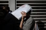 Una donna si ripara dal sole con i propri documenti (© Paolo Valenti/lavialibera)